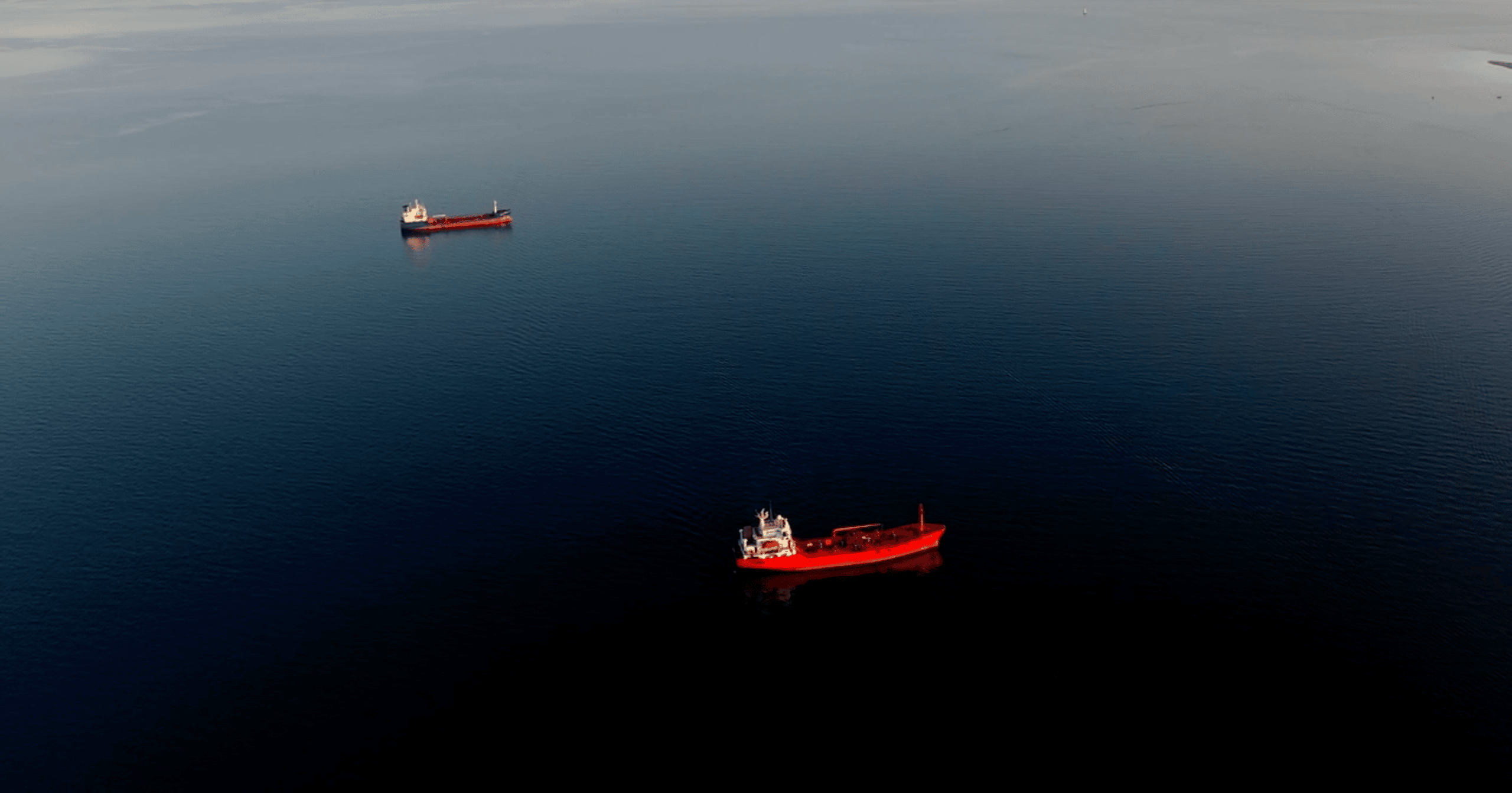 Two red tankers on the ocean associated with the Grieg Shipbrokers tank services.
