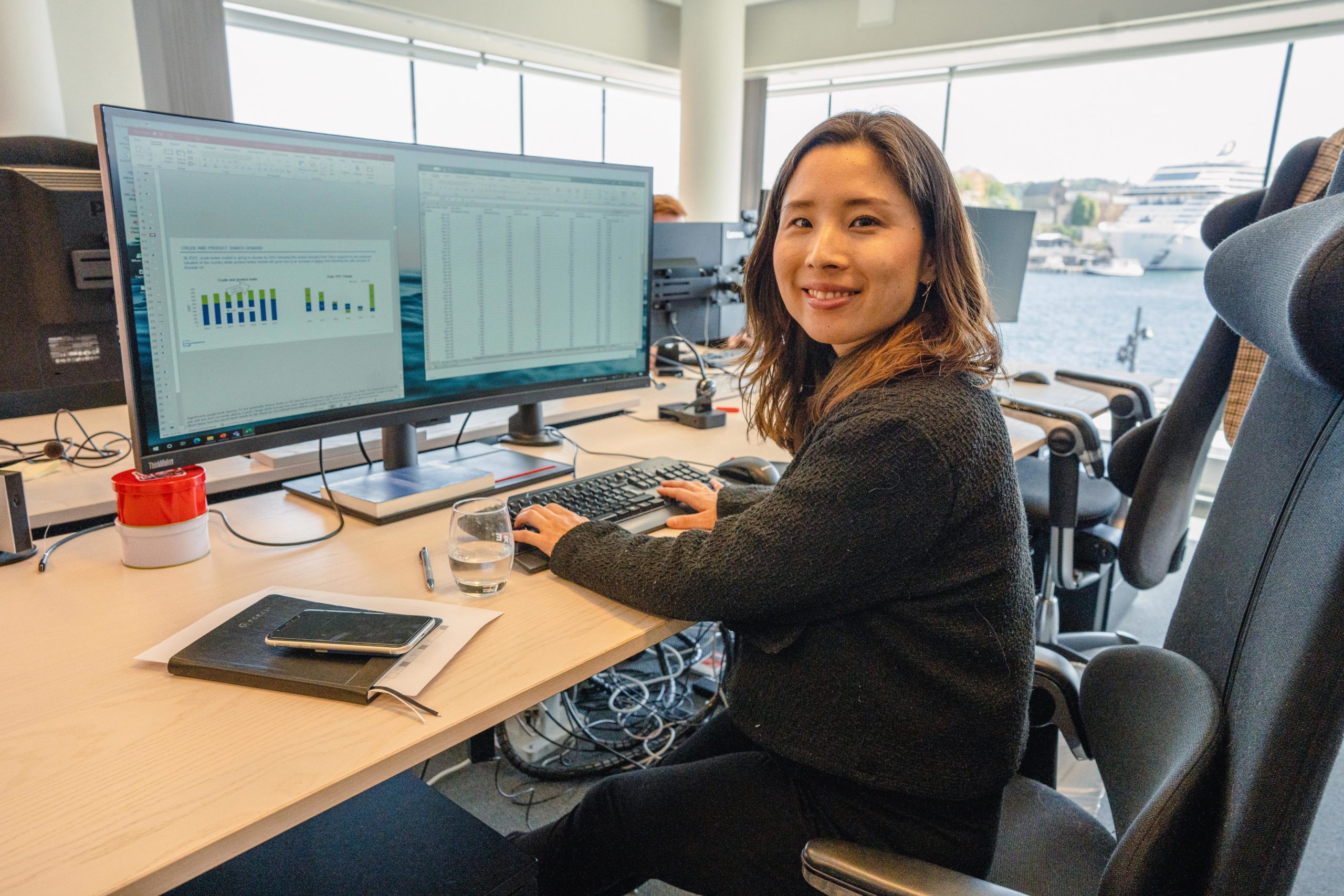 Grieg Shipbroker female employee smiling while she is working with analytics at the office.