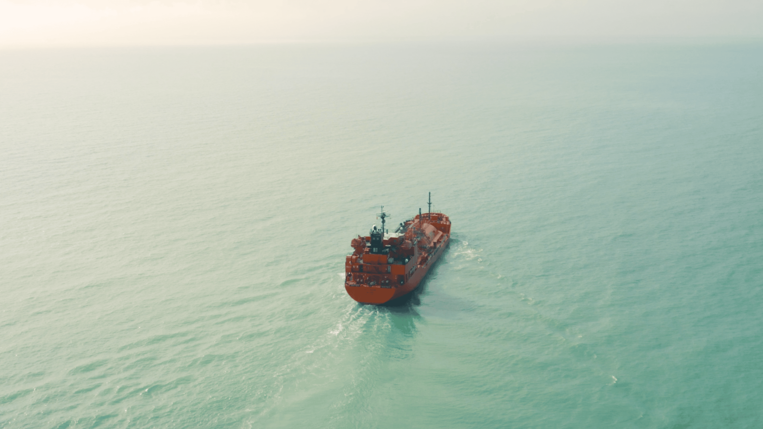 One of Grieg Shipbrokers' red gas ship in a open landscape on the ocean.